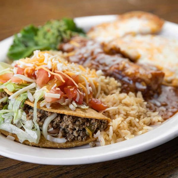 Pecina's Mexican Cafe's crispy beef taco with lettuce, tomatoes, cheese, rice, beans, and guacamole.