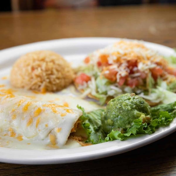 A Pecina's Mexican Cafe plate with a cheese enchilada, rice, tostada, and guacamole.