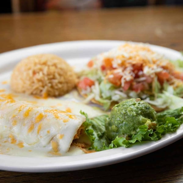 A Pecina's Mexican Cafe combo plate with a cheesy burrito, rice, tostada, and guacamole.